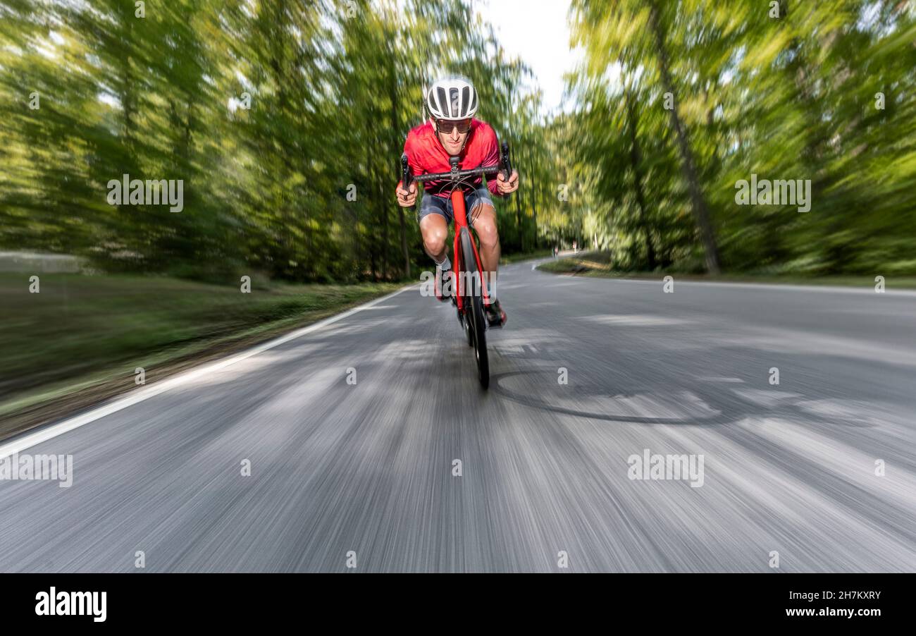 Cycliste mâle longeant la route de l'asphalte de la forêt Banque D'Images