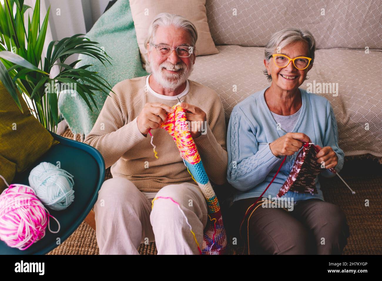 Couple senior souriant triant de la laine à la maison Banque D'Images