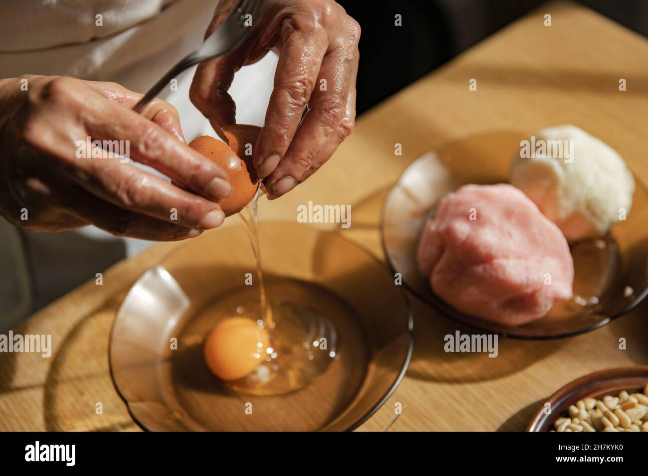 Femme cassant un œuf dans un bol de cuisine Banque D'Images