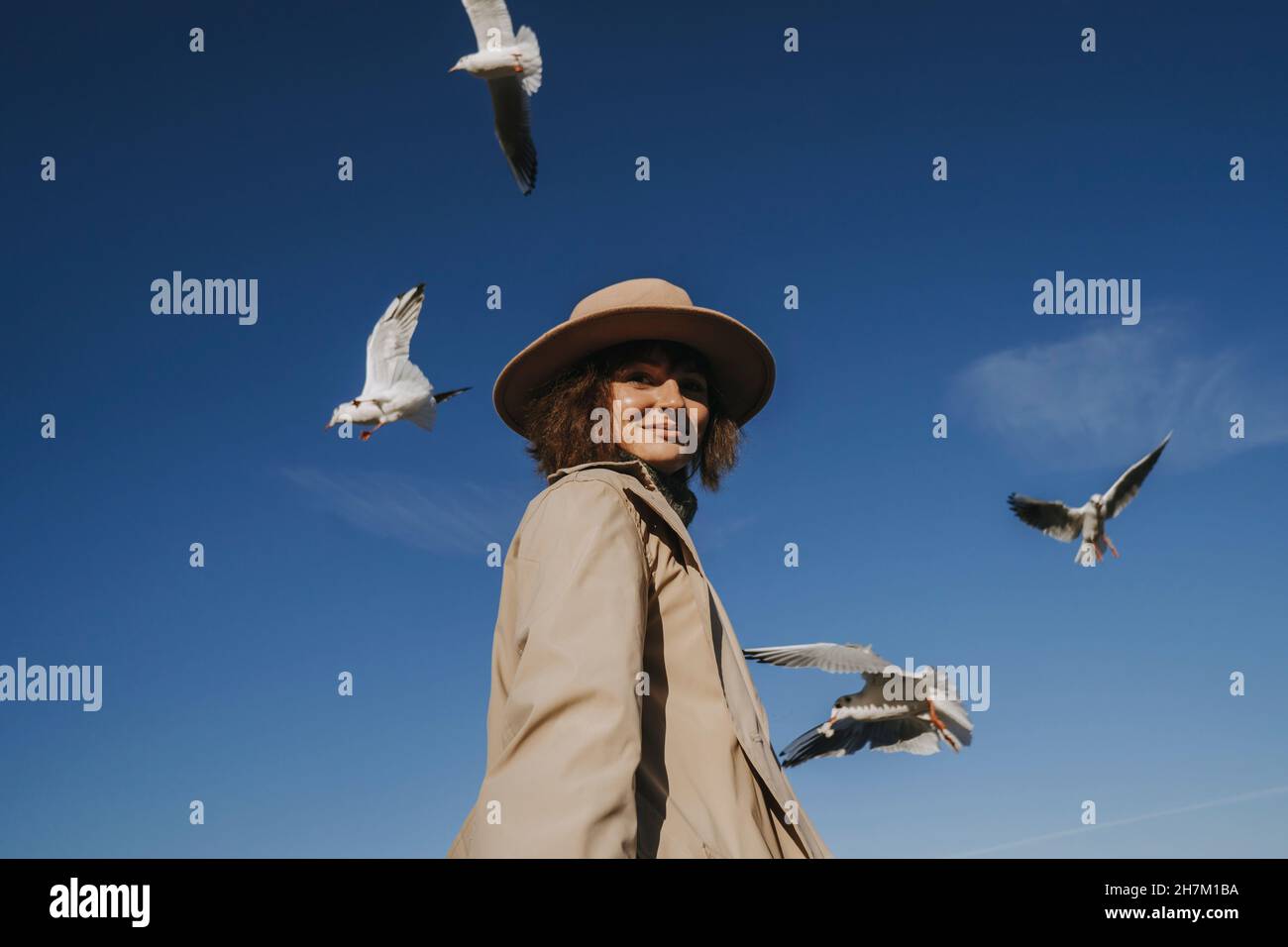 Femme souriante avec des mouettes volantes au-dessus de la tête Banque D'Images