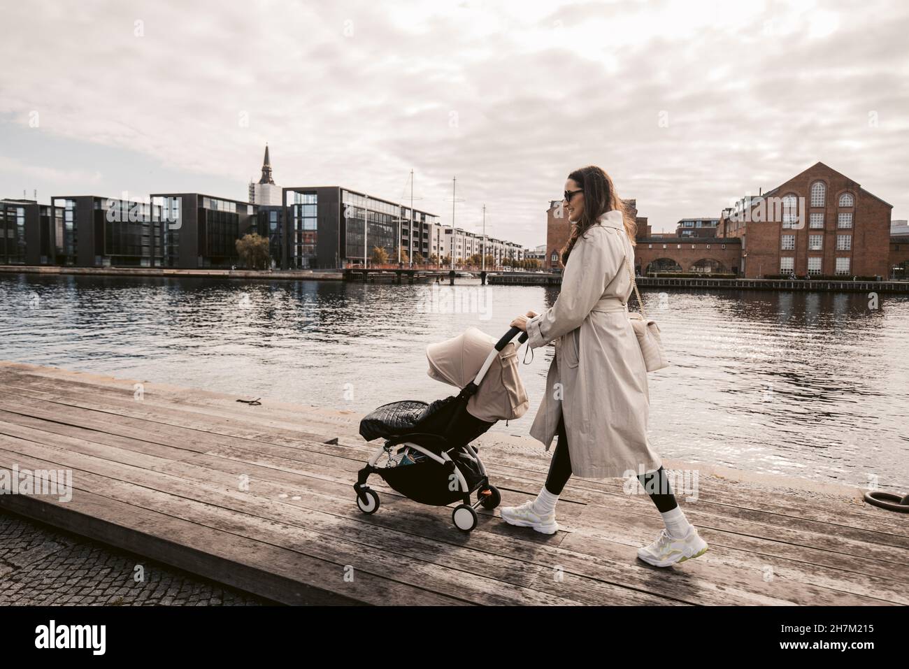 Femme marchant avec une poussette sur la jetée par le canal à Copenhague, Danemark Banque D'Images