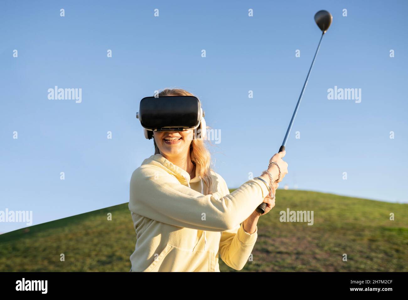 Couple heureux jouant au golf sur la colline au coucher du soleil Banque D'Images
