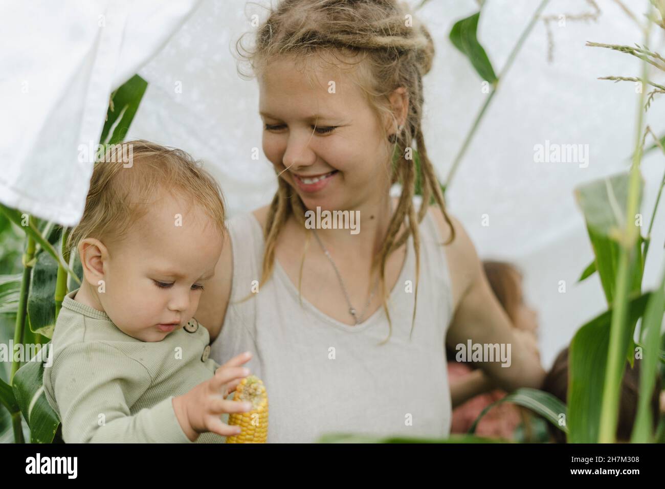 Mère souriante regardant la petite fille dans le champ de maïs Banque D'Images