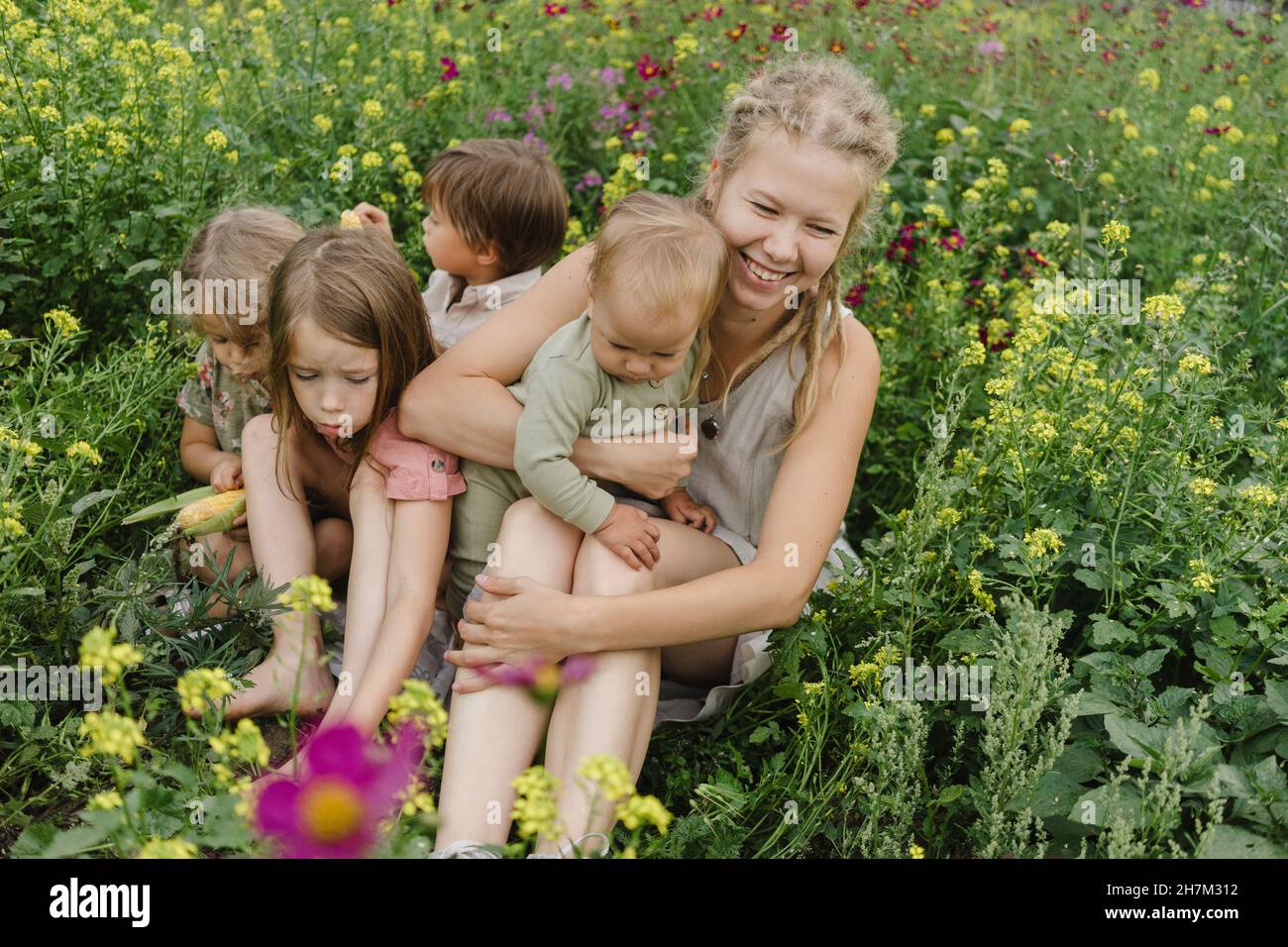 Famille heureuse assise parmi les plantes Banque D'Images