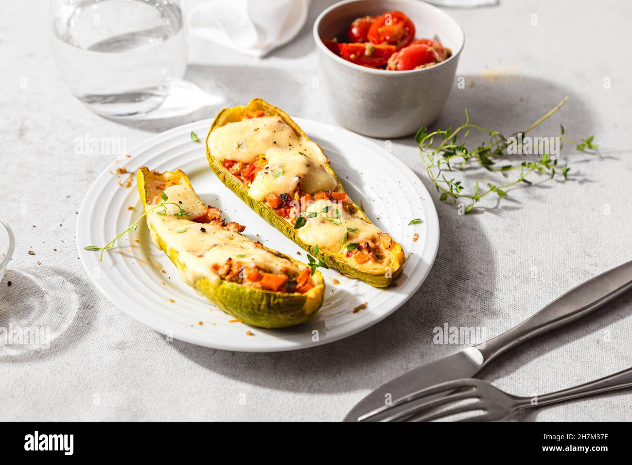 Courgettes farcies fraîches avec tomates cerises et fromage dans une assiette Banque D'Images