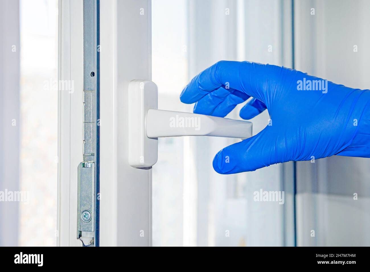 La personne qui porte des gants de protection en caoutchouc ouvre la poignée de la porte pendant l'éclosion du virus de la grippe covid, l'épidémie du coronavirus et les maladies infectieuses Banque D'Images