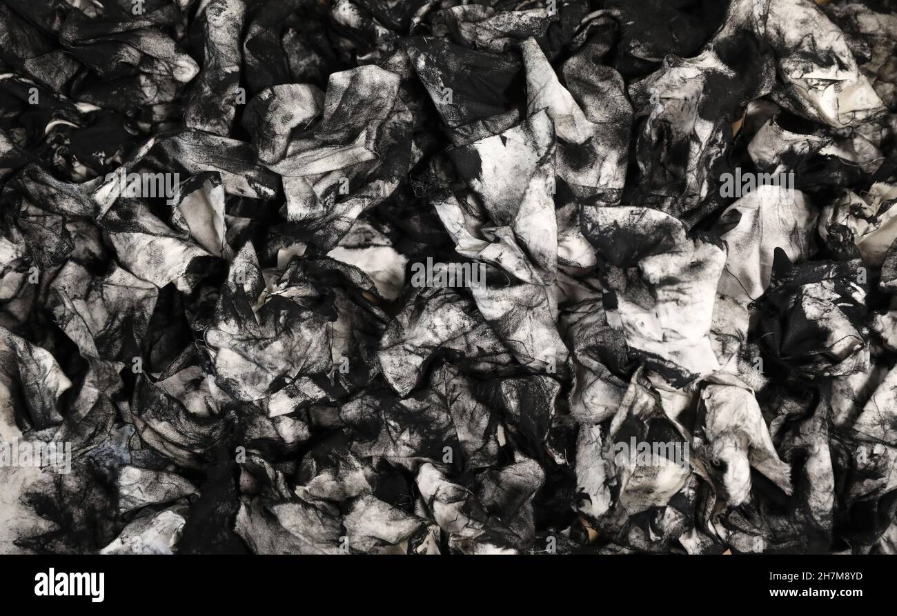 Une masse de chiffons sales et usagés recouverts d'encre noire pour imprimantes.Il peut également s'agir de lingettes pour jauge d'huile provenant d'un mécanicien.Dos noir et blanc abstrait unique Banque D'Images