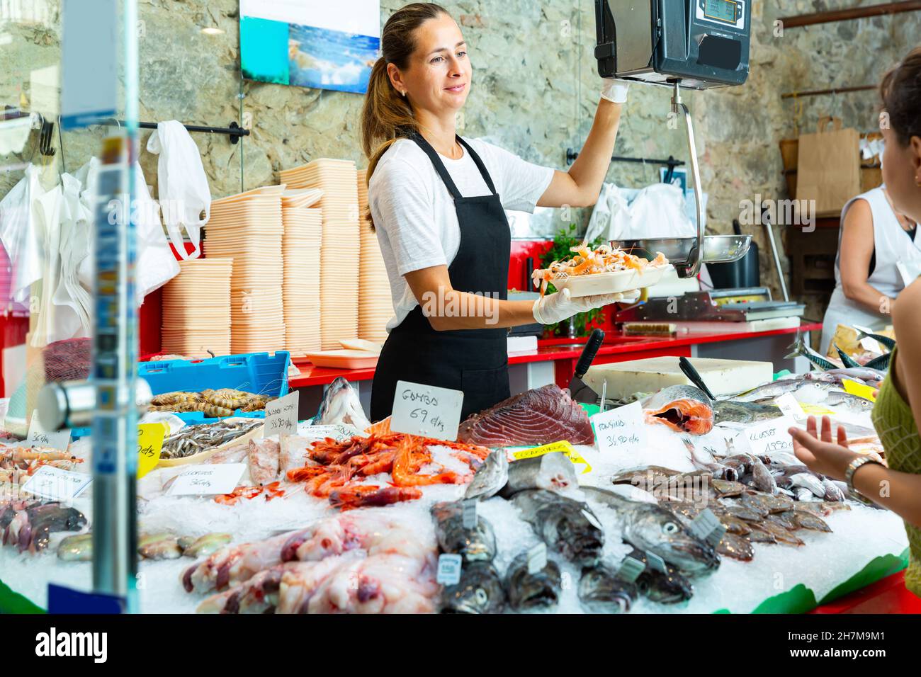 Femelle ordinaire pesant des crevettes crues sur des balances Banque D'Images