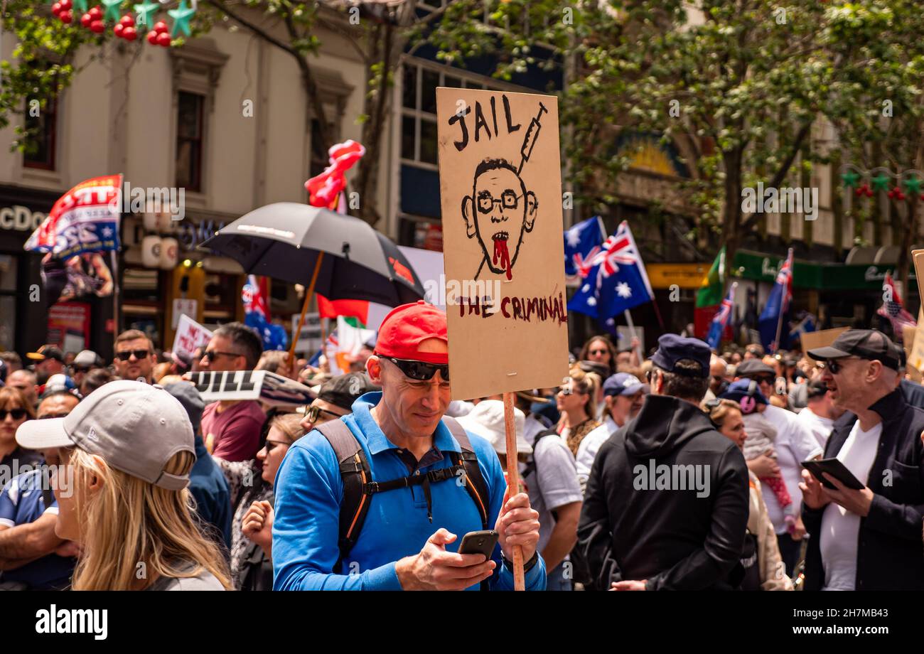 Melbourne, Victoria Australie - novembre 20 2021 : homme en chemise bleue et texte de casquette rouge sur le téléphone tout en tenant une prison Daniel Andrews signe sur Bourke S. Banque D'Images