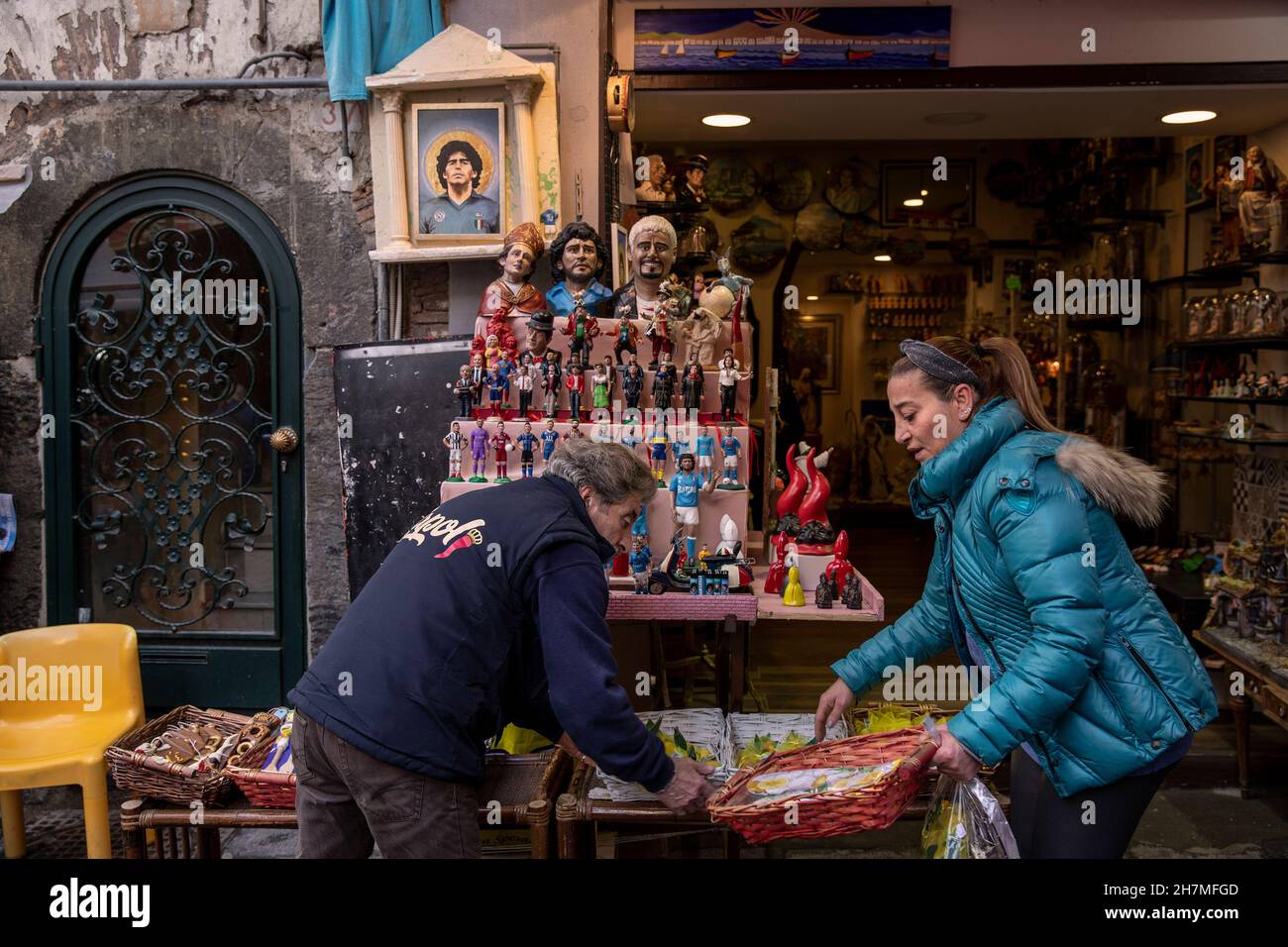 Neapel, Italie.23 novembre 2021.Un homme et une femme préparent un stand avec des souverains dans la rue San Gregorio Armeno, où également de petites et plus grandes figures de la légende du football Maradona sont offertes.Un an après la mort de la star du football dans une résidence privée au nord de Buenos Aires, Maradona est commémoré avec des hommages, des séries télévisées et des mémoriaux - également à Naples, où le 'Golden boy' a joué pendant des années dans la SSC Naples.(À dpa 'Un an sans Diego: Hommages et accusations à l'anniversaire de la mort de Maradona') Credit: Alessio Paduano/dpa/Alay Live News Banque D'Images