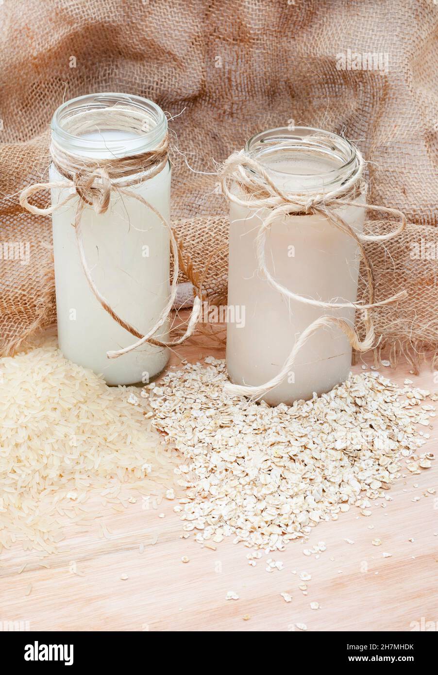 Lait de riz avec grains de riz en vrac et lait d'avoine avec avoine crue sur une table rustique avec espace de copie Banque D'Images