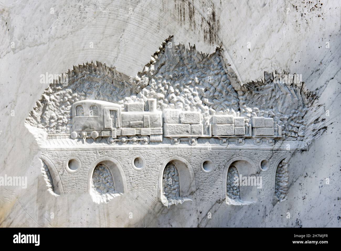 Prenez un train avec des cargaisons sur un pont de chemin de fer voûté sculpté sur un mur en marbre blanc Banque D'Images
