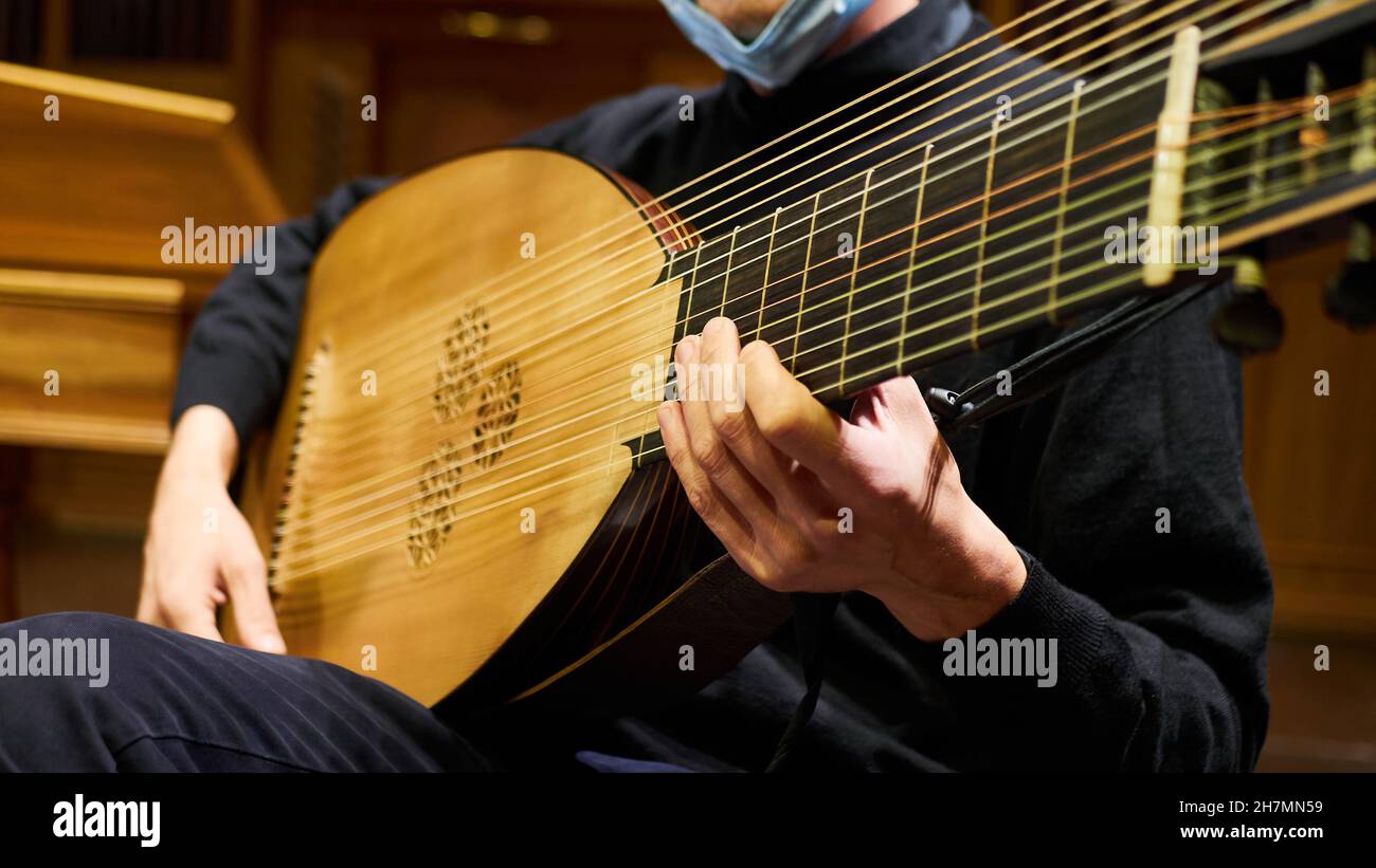 Un musicien de personne joue un théorbo baroque de luth avec ses mains les cordes pendant un concert. Banque D'Images