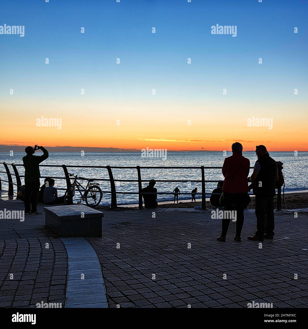 Visiteurs sur la promenade du front de mer, Silhouettes après le coucher du soleil, Cardigan Bay, Aberystwyth, Ceredigion,Pays de Galles, Royaume-Uni Banque D'Images