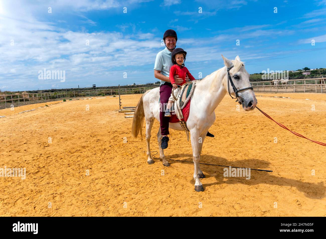 Père et fils profitant de l'équitation dans le paddock Banque D'Images