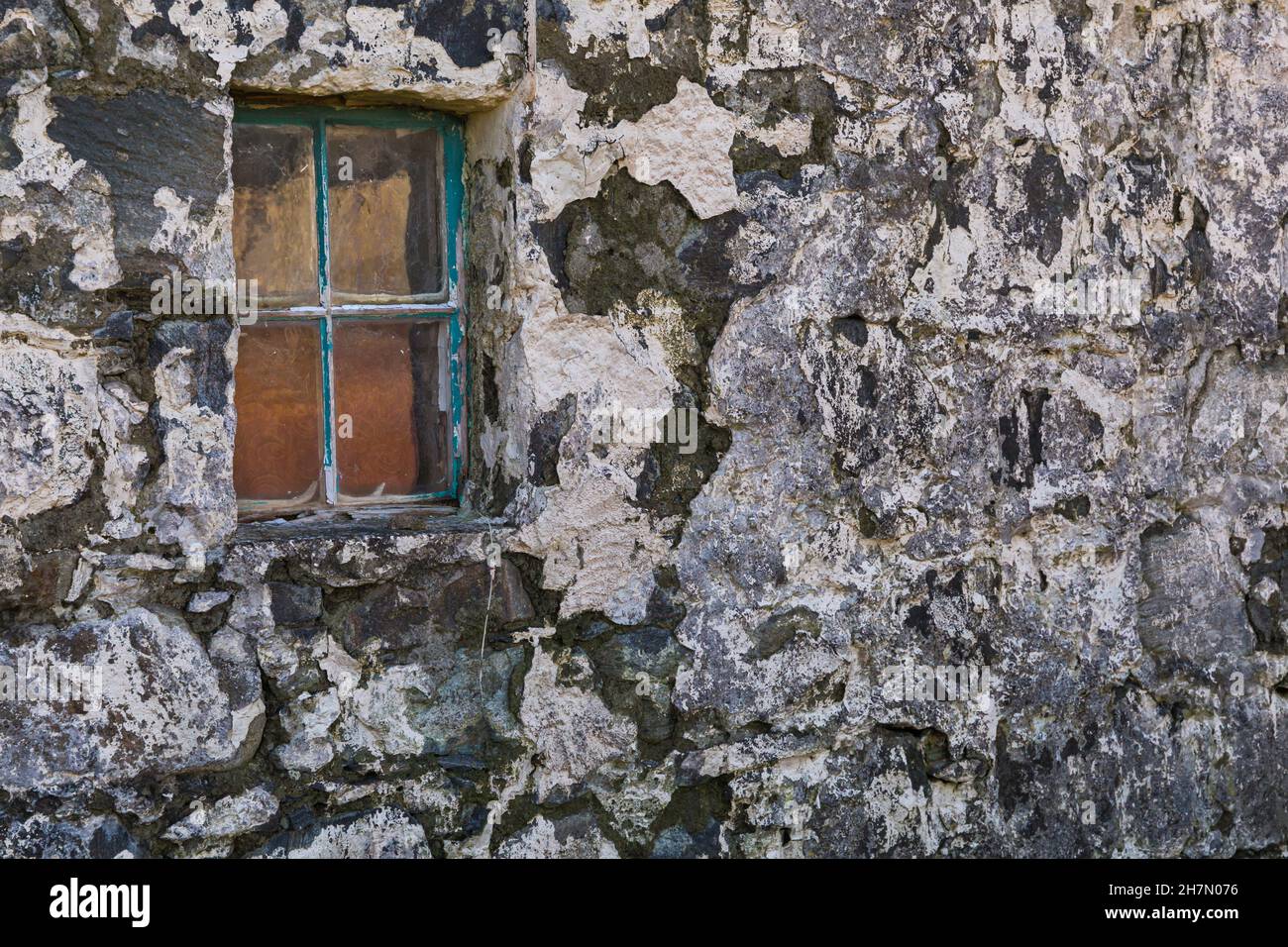 Gros plan des détails des couleurs reflétées dans la vieille fenêtre et le mur de la maison abandonnée croft à l'île de Harris, Outer Hebrides, Écosse Royaume-Uni en novembre Banque D'Images