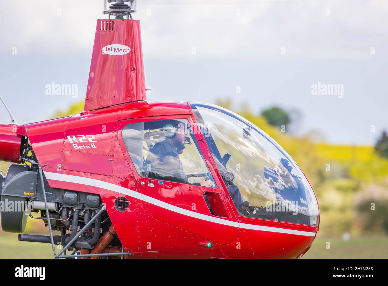 Vue latérale gros plan d'un pilote à l'intérieur d'un hélicoptère Red R22 Beta II, au départ de l'aérodrome de Halfpenny Green, au Royaume-Uni, connu localement sous le nom d'aéroport de Bobbington. Banque D'Images