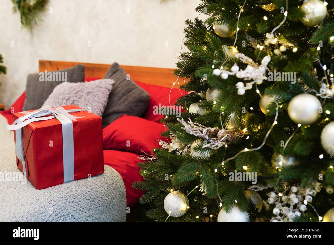 Cadeau de Noël rouge dans la chambre.Décoration intérieure confortable, lit  en bois, sapin du nouvel an décoré de jouets et de guirlandes Photo Stock -  Alamy