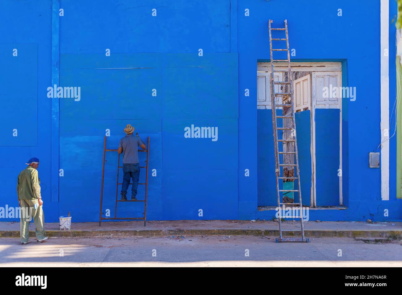 TRINIDAD, CUBA - 7 JANVIER 2021 : un ouvrier cubain peint à l'extérieur de la maison en bleu le 7 janvier 2021 à Trinidad.Les maisons à Cuba doivent être Banque D'Images
