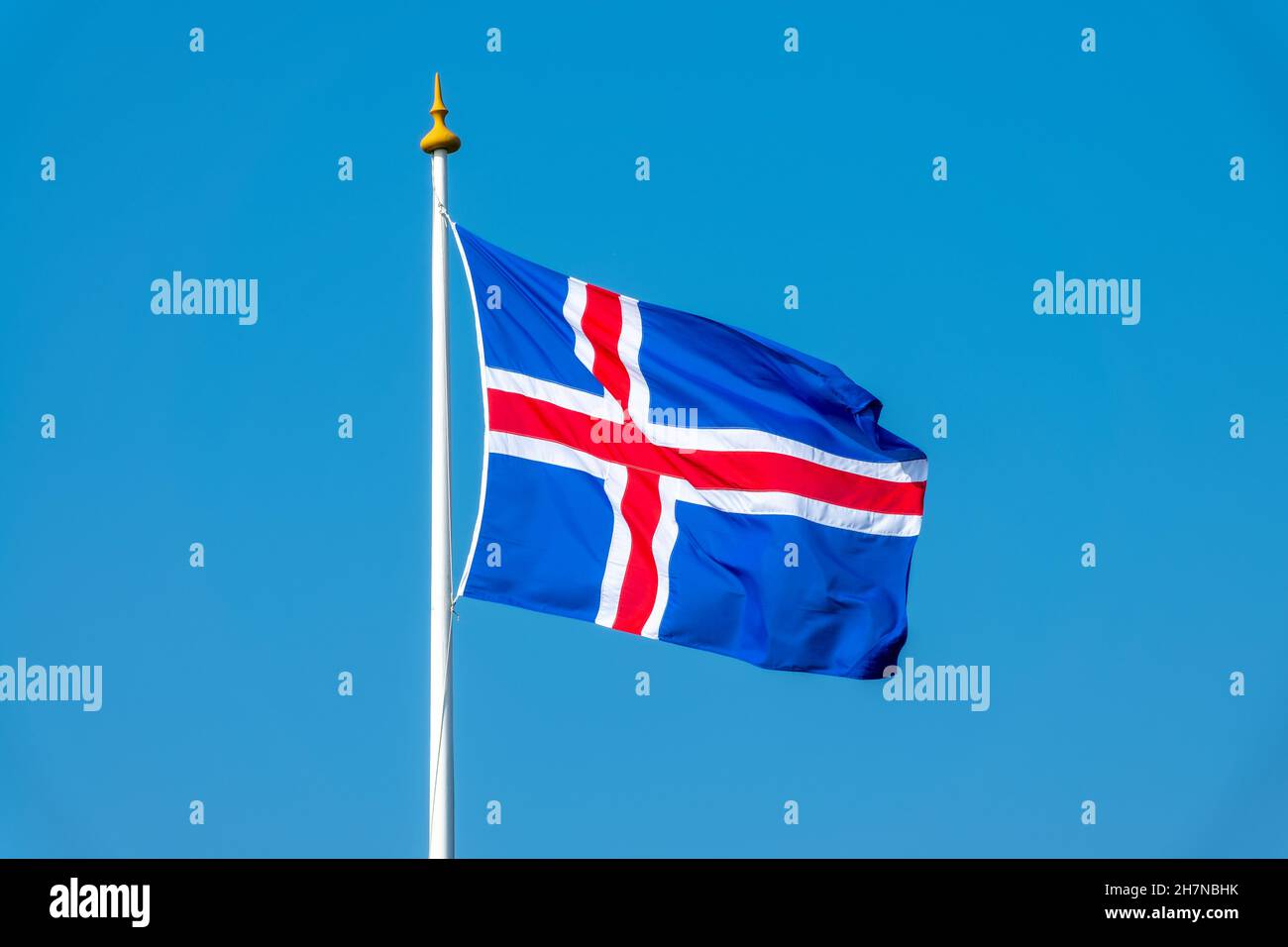 Drapeau islandais sur un poteau flottant dans le vent sur fond bleu ciel Banque D'Images