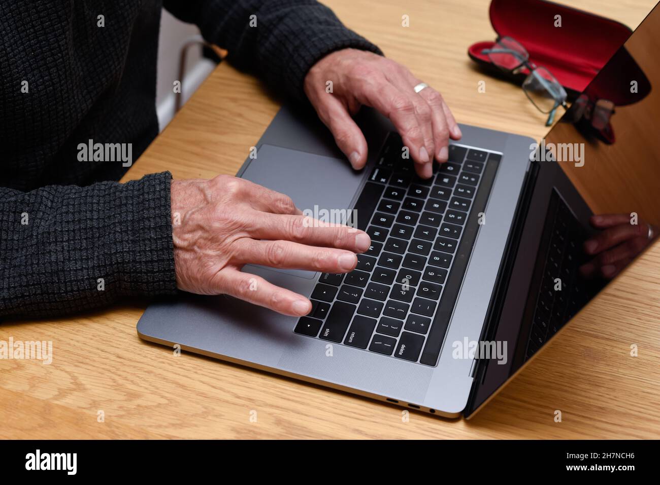Homme senior utilisant un ordinateur portable à la maison avec gros plan sur les mains sur le clavier Banque D'Images