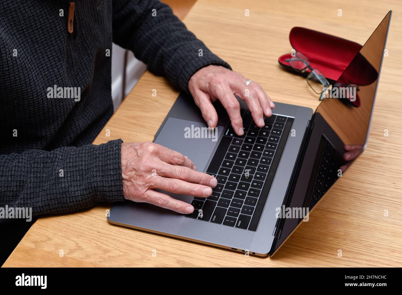 Homme senior utilisant un ordinateur portable à la maison avec gros plan sur les mains sur le clavier Banque D'Images