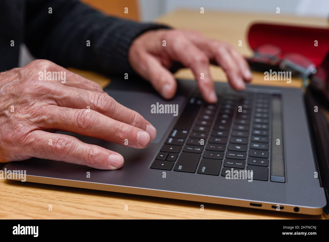 Homme senior utilisant un ordinateur portable à la maison avec gros plan sur les mains sur le clavier Banque D'Images