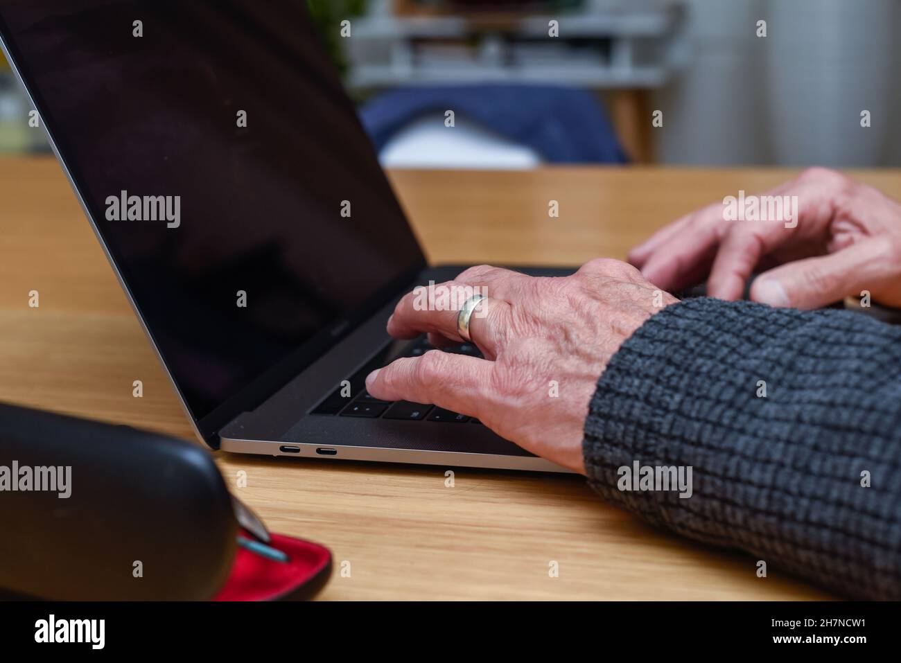 Homme senior utilisant un ordinateur portable à la maison avec gros plan sur les mains sur le clavier Banque D'Images