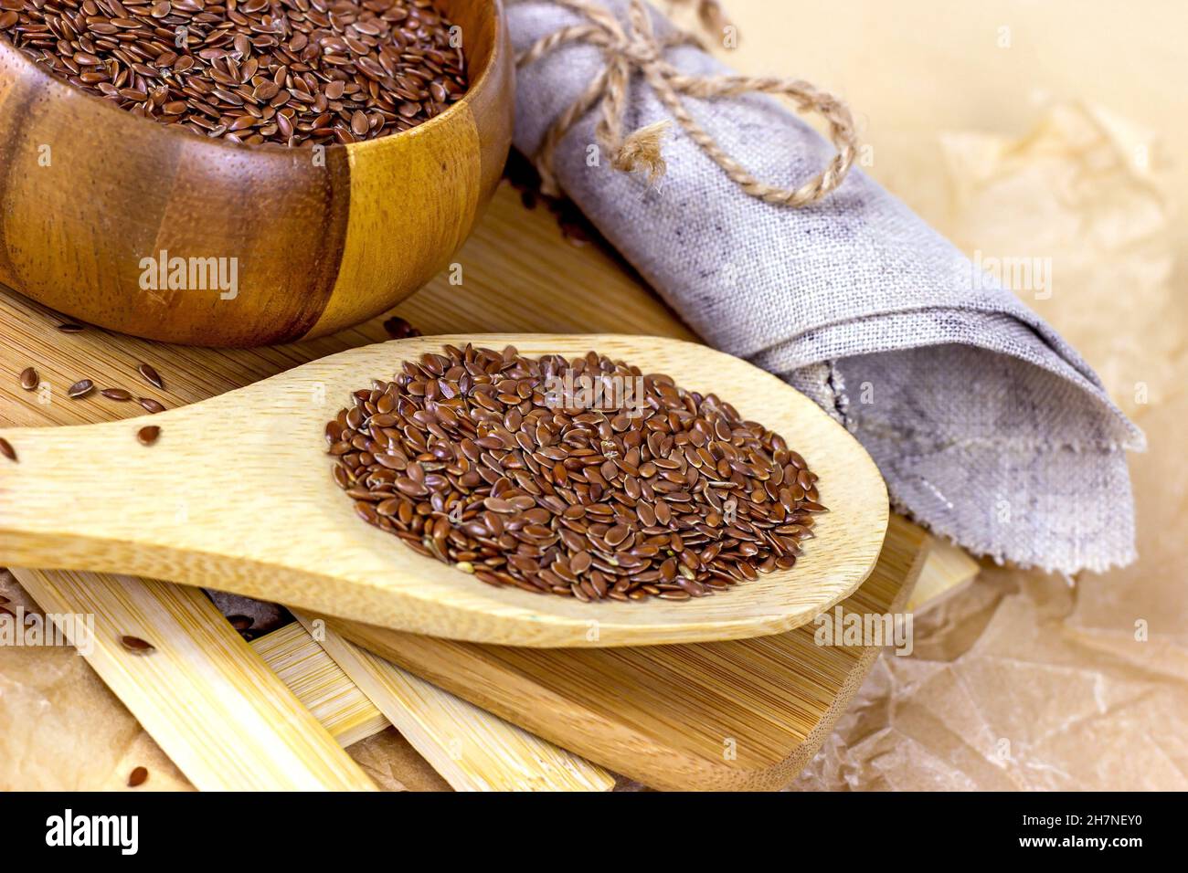 Faire dorer les graines de lin sèches dans une cuillère en bois et les mettre sur un fond clair. Banque D'Images