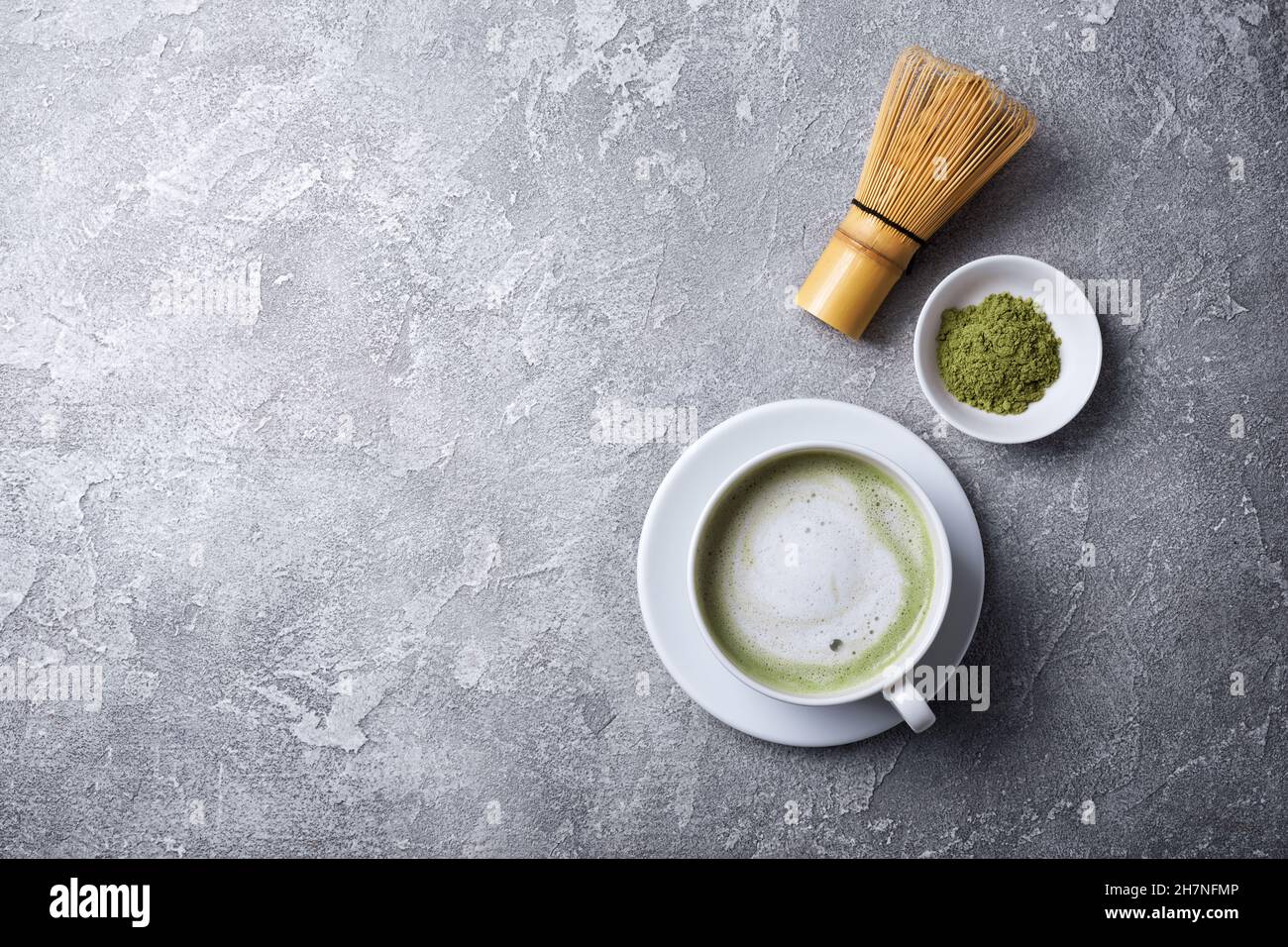 Vue de dessus de thé vert de matcha biologique ou de latte avec fouet en bambou sur fond de béton gris avec espace de copie Banque D'Images