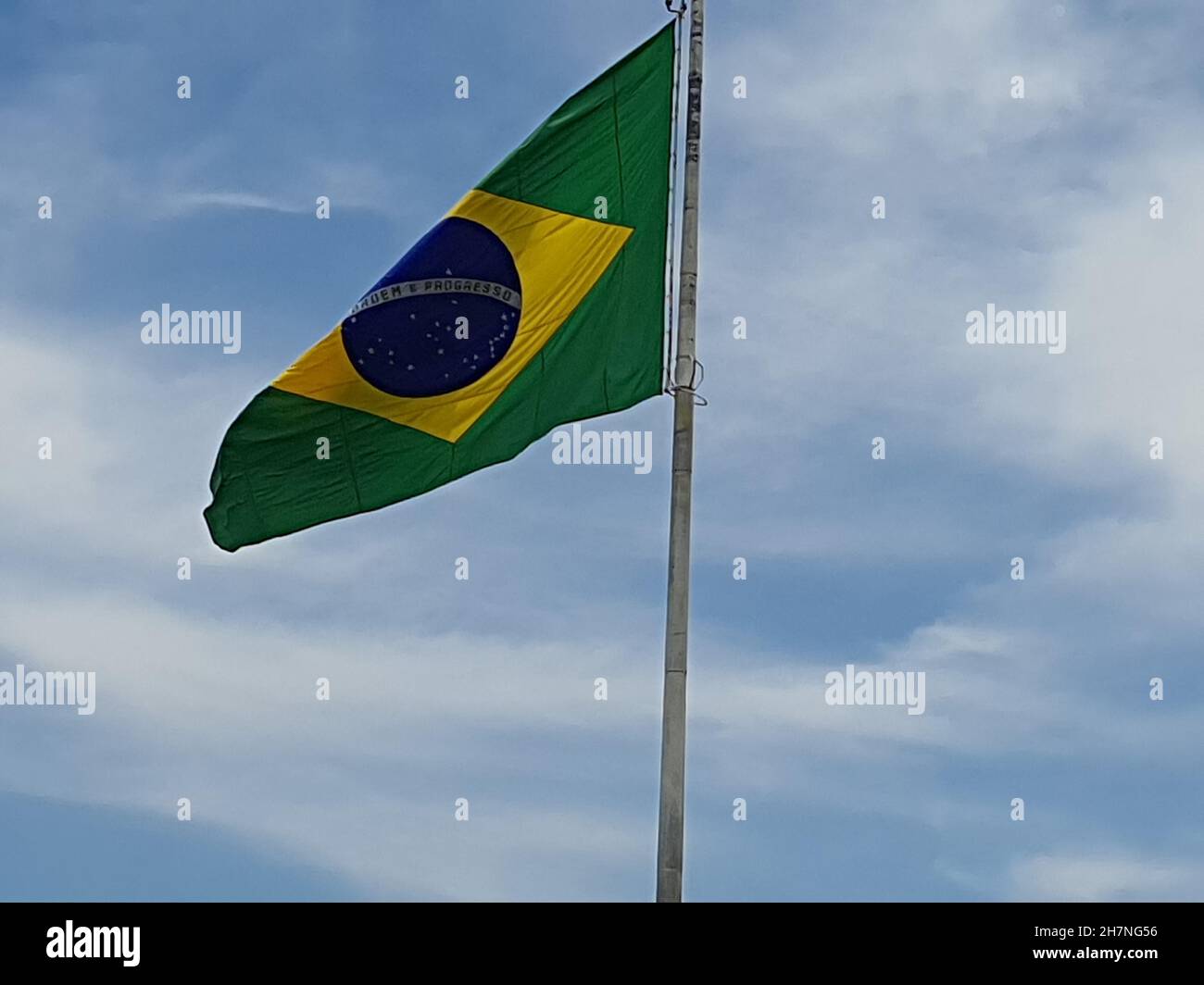 Drapeau du Brésil, sur un poteau dans le fond du ciel bleu. Banque D'Images
