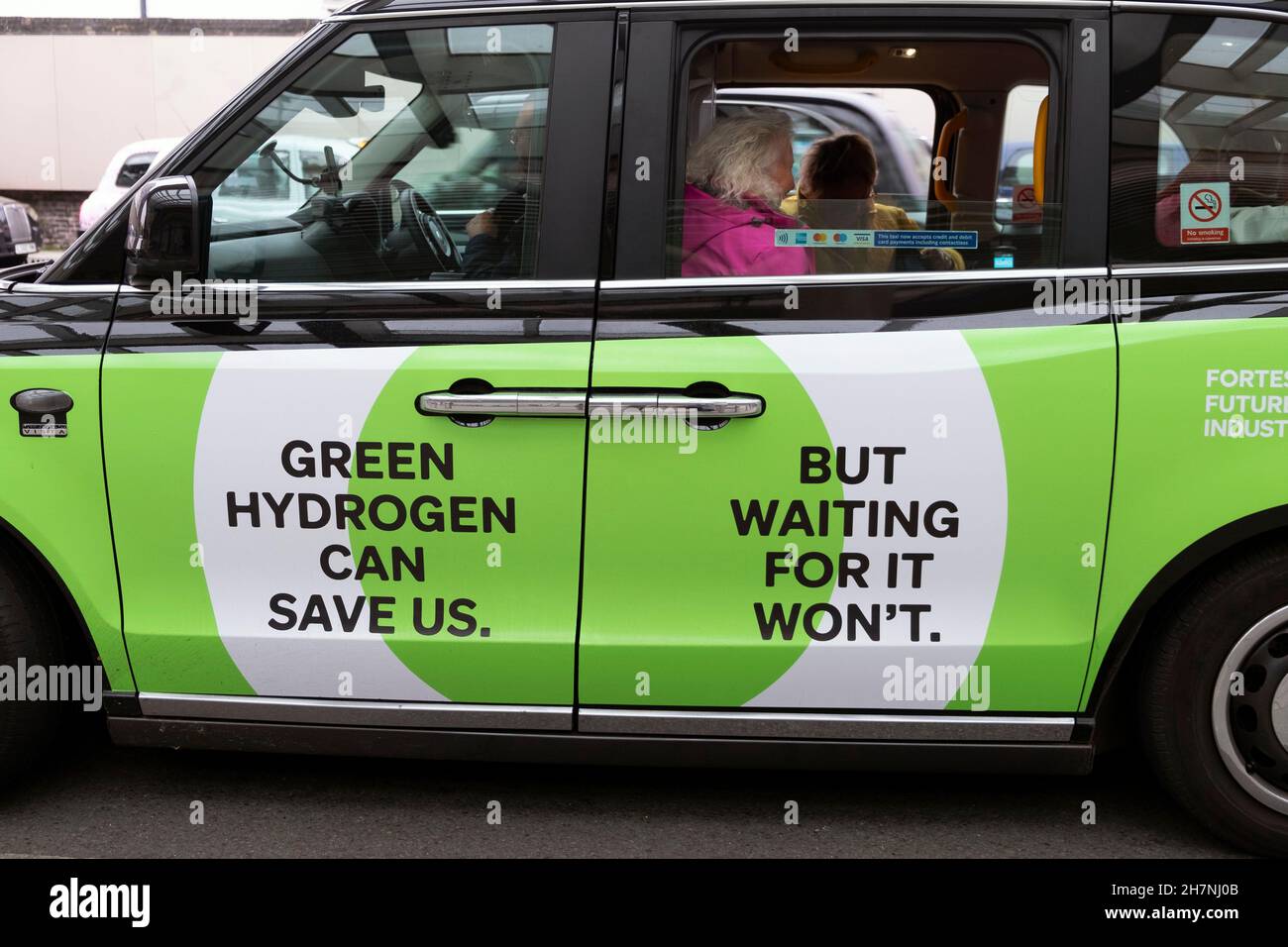 L'HYDROGÈNE VERT PEUT NOUS SAUVER. MAIS EN ATTENDANT ÇA NE SERA PAS Publicité FFI carburant sur le côté d'un taxi noir à la gare de Paddington à Londres Royaume-Uni KATHY DEWITT Banque D'Images