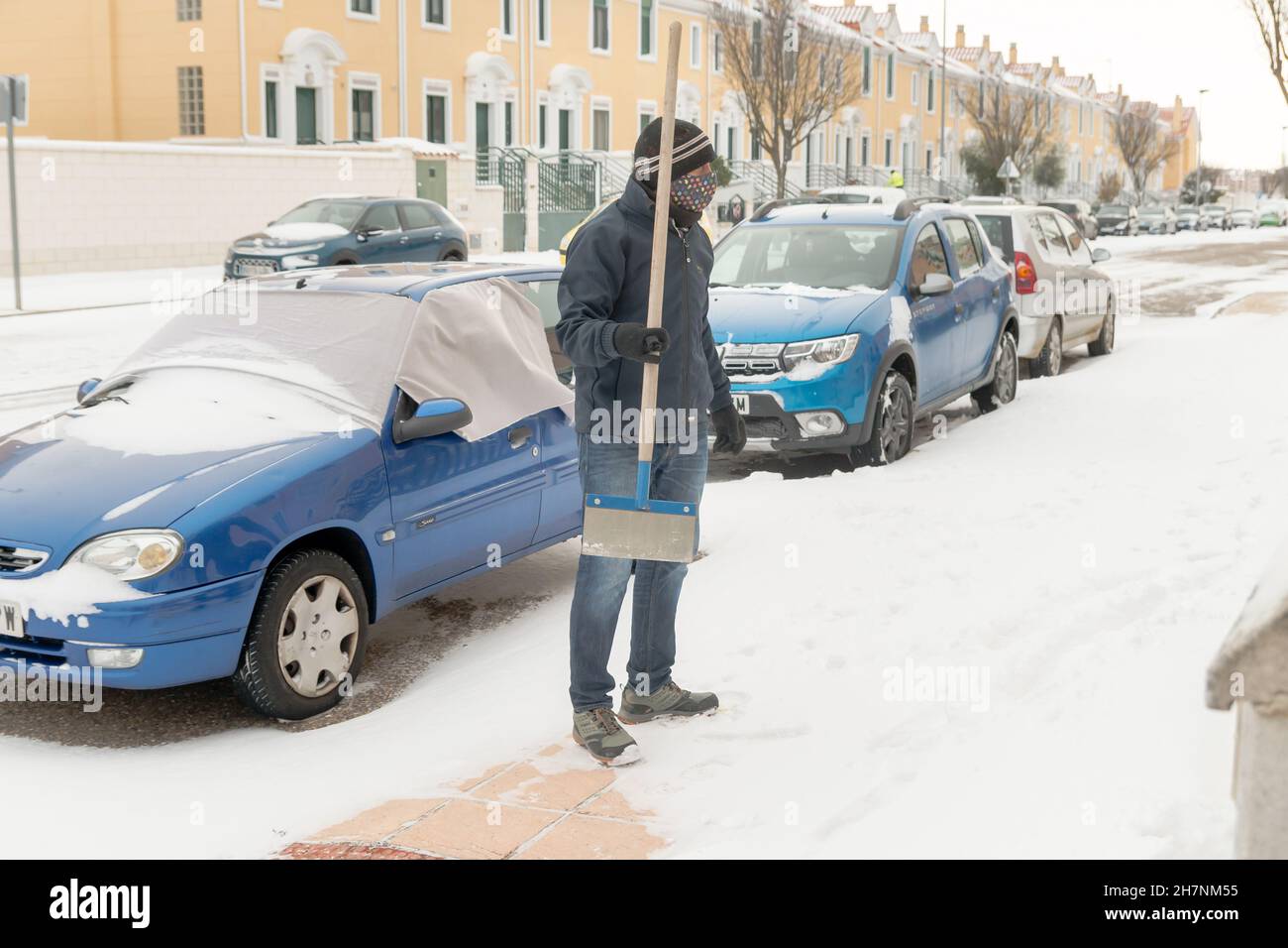 Un homme avec un grattoir se prépare à enlever la neige du sol dans une urbanisation pendant l'hiver froid à Zamora, en Espagne. Banque D'Images