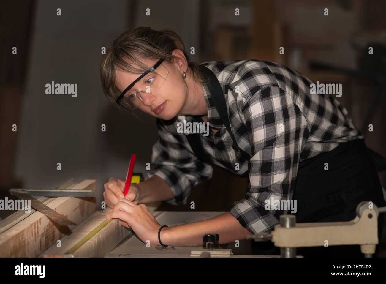 Femme charpentier prenant la mesure d'une planche en bois Banque D'Images