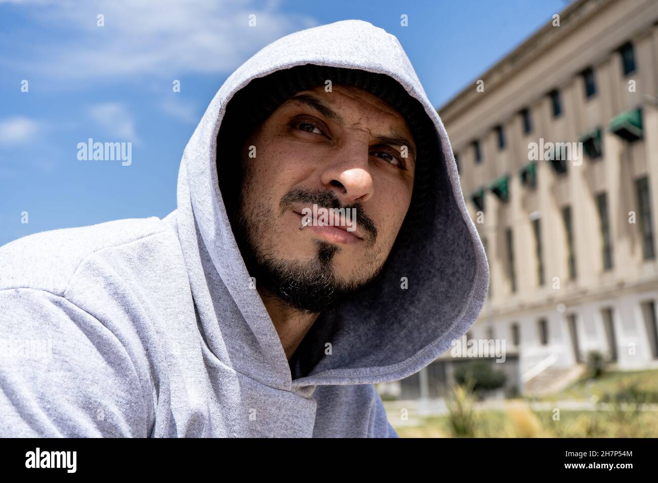 Un PORTRAIT d'un jeune Latino avec un sweat à capuche gris à l'infini.Style urbain marginal. Banque D'Images