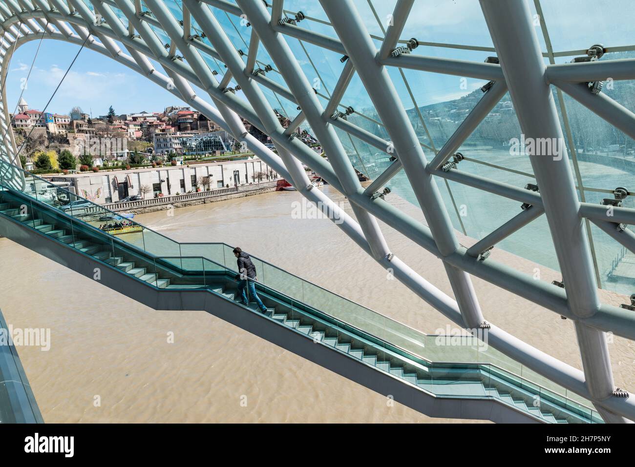 Piéton marchant dans les escaliers de l'emblématique pont de la paix au-dessus de la rivière Kura à Tbilissi, Géorgie, Caucase Banque D'Images