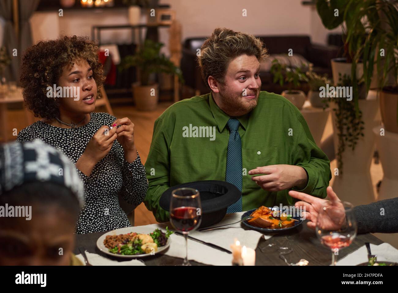 Couple multiethnique parlant à leurs amis pendant la réunion au dîner Banque D'Images