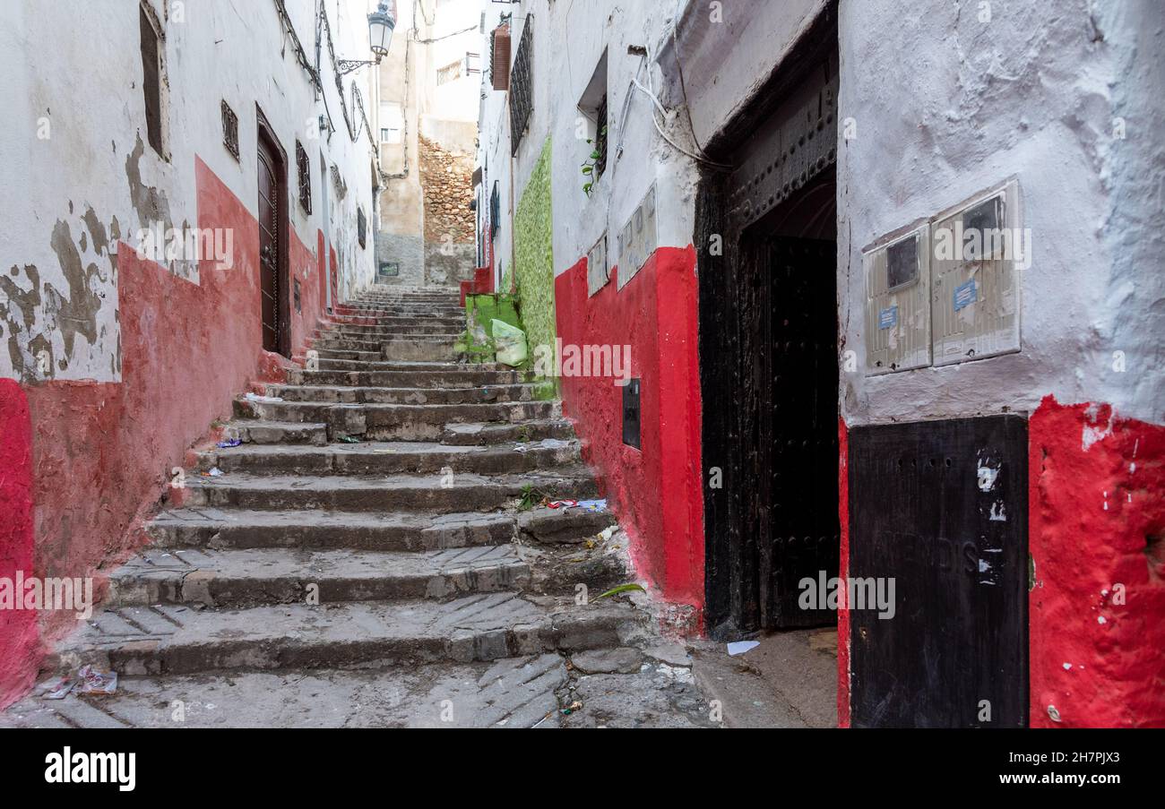 Dans la médina de Tétouan au Maroc.Un vieux escalier monte dans une allée entre les murs peints dans des couleurs vives, rouge et vert Banque D'Images
