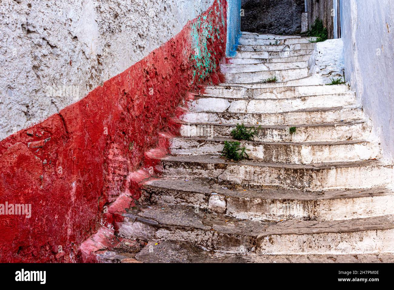 Dans la médina de Tétouan au Maroc.Un vieux escalier monte jusqu'à une maison entre les murs peints dans des couleurs vives, rouge et blanc Banque D'Images