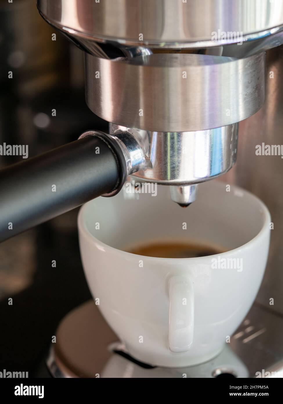 Gros plan d'un café versé dans une tasse en céramique blanche à partir d'une machine à café Banque D'Images