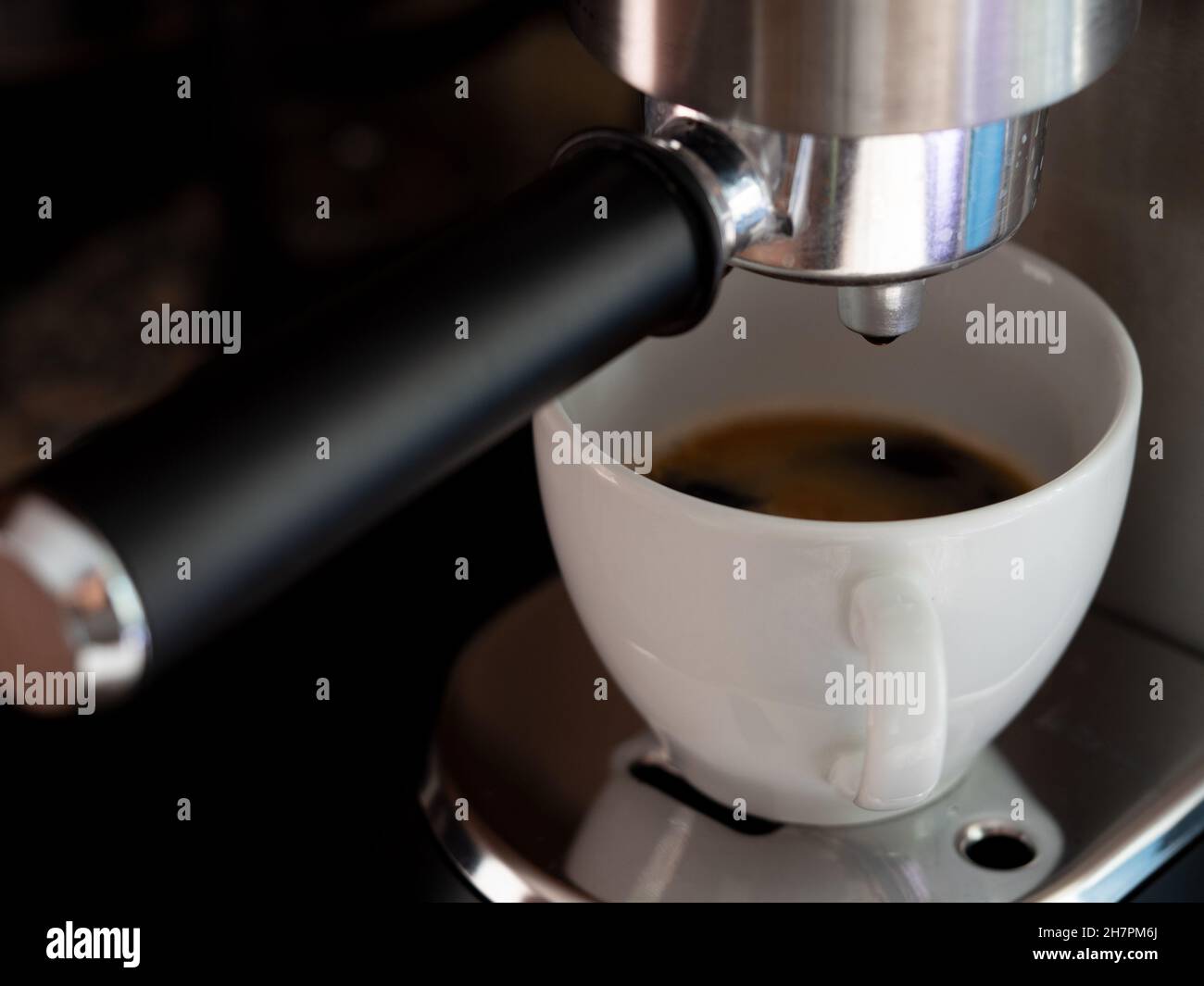 Gros plan d'un café versé dans une tasse en céramique blanche à partir d'une machine à café Banque D'Images