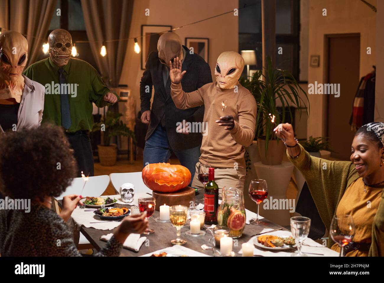 Groupe d'amis en costumes s'amusant à la table pendant la fête d'Halloween dans la salle Banque D'Images