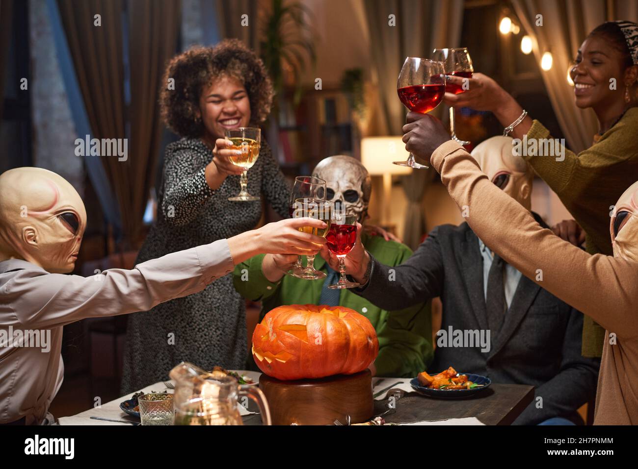Groupe d'amis heureux de griller avec des verres de vin rouge et de célébrer Halloween pendant la fête à la maison Banque D'Images