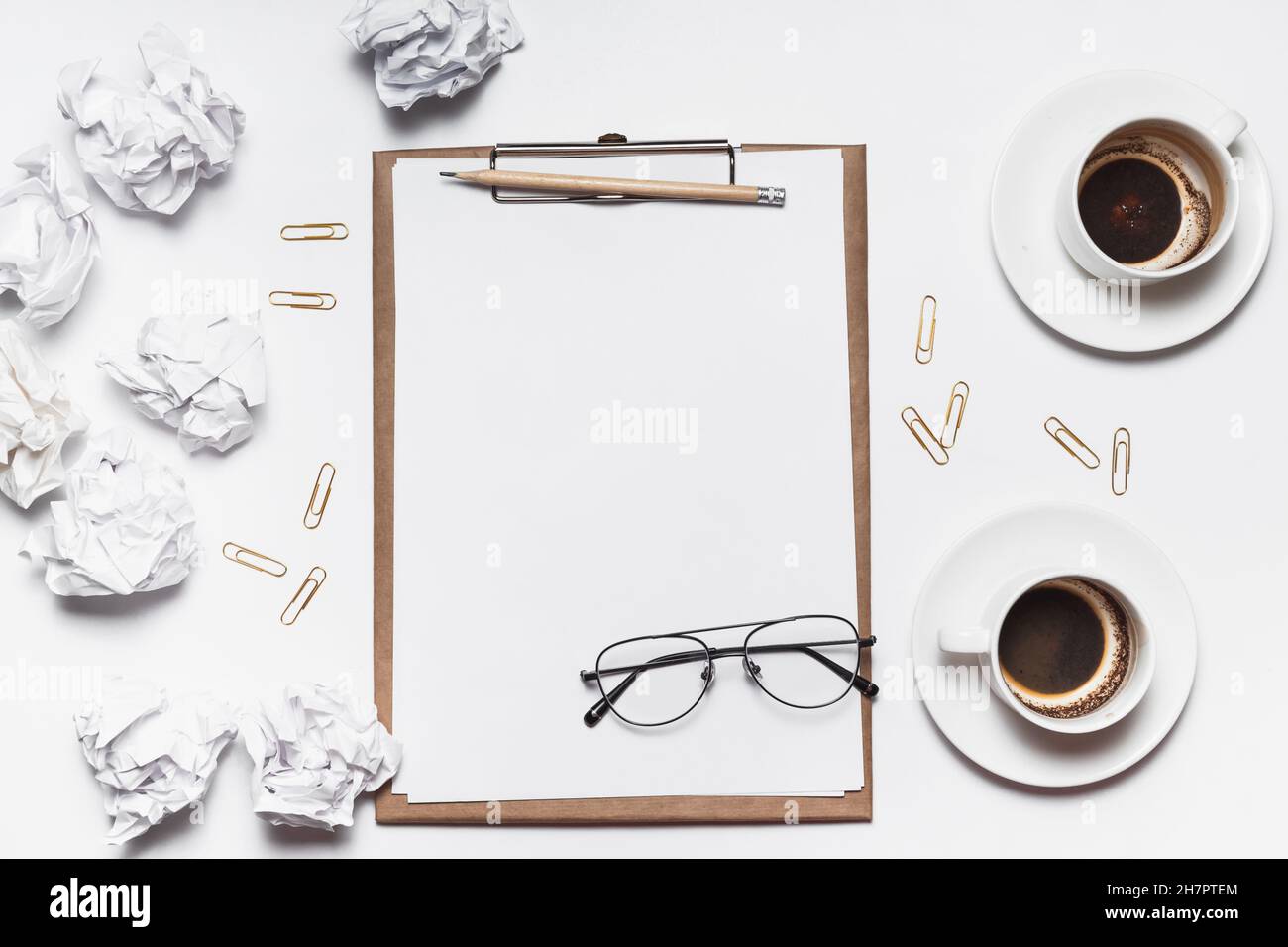 Des papiers froissés éparpillés, des tasses vides de café sur la table d'un travailleur de la création. Crise créative. Concept de stress, de troubles de santé mentale et de manque de moi Banque D'Images