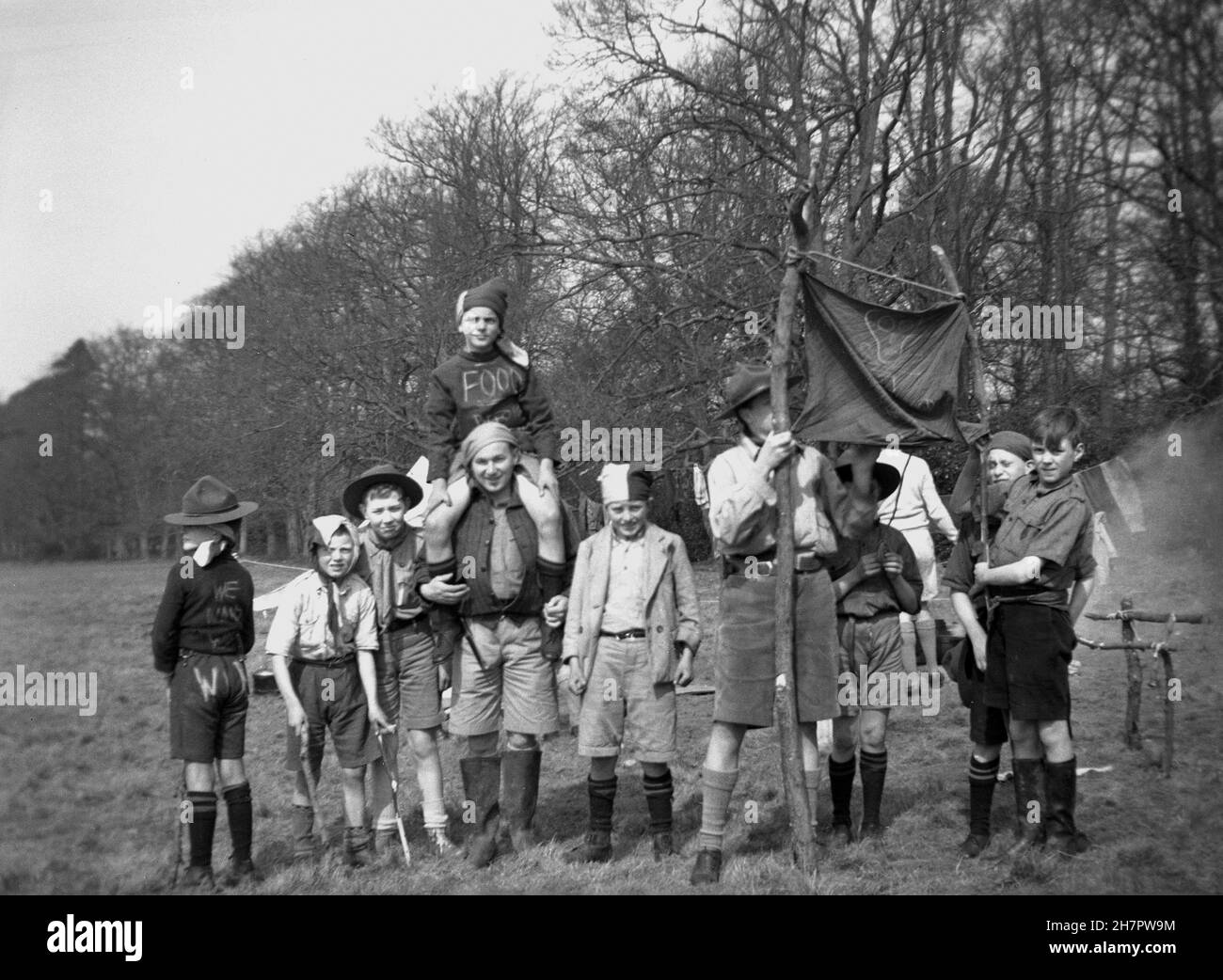 1939, historique, camp scout, maître scout féminin avec un groupe de scouts de cub dans le champ, al en uniforme, mais certains vêtus de renoncer à une procession communiste, Angleterre, Royaume-Uni. Banque D'Images