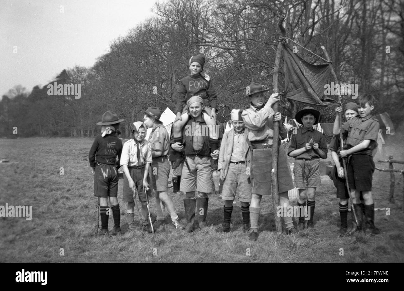 1939, historique, camp scout, maître scout féminin avec un groupe de scouts de cub dans le champ, al en uniforme, mais certains vêtus de renoncer à une procession communiste, Angleterre, Royaume-Uni. Banque D'Images