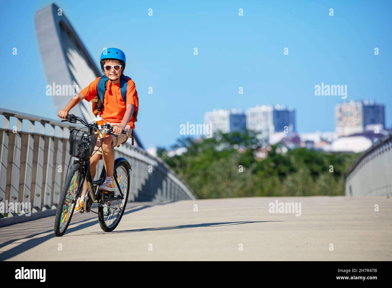 Un garçon fait du vélo depuis l'école dans la grande ville Banque D'Images