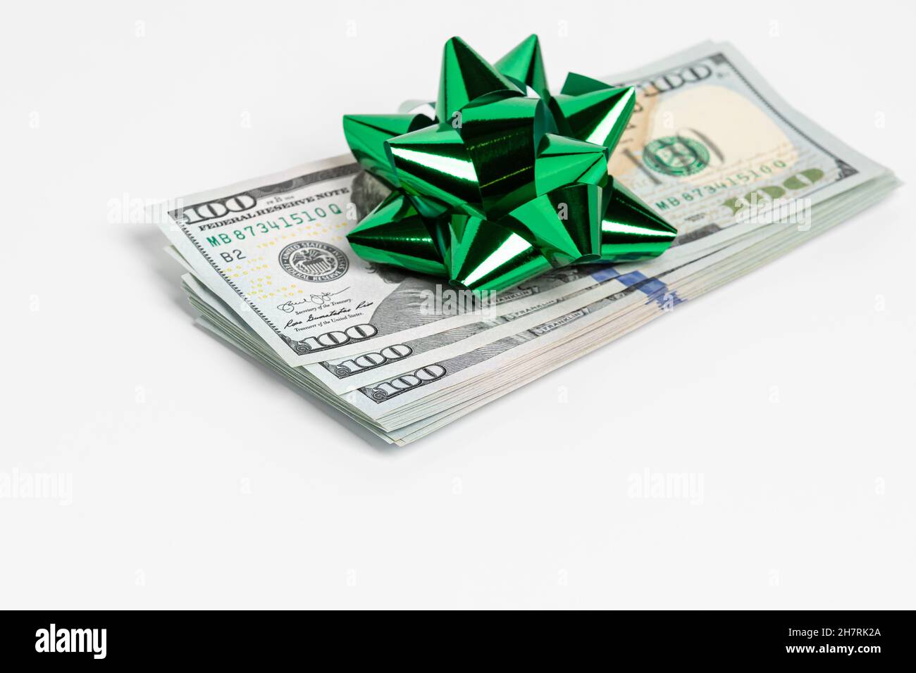 Cadeau en argent comptant de billets de 100 $ avec noeud vert.Concept de la taxe sur les cadeaux, du don de bienfaisance et du cadeau de fête. Banque D'Images