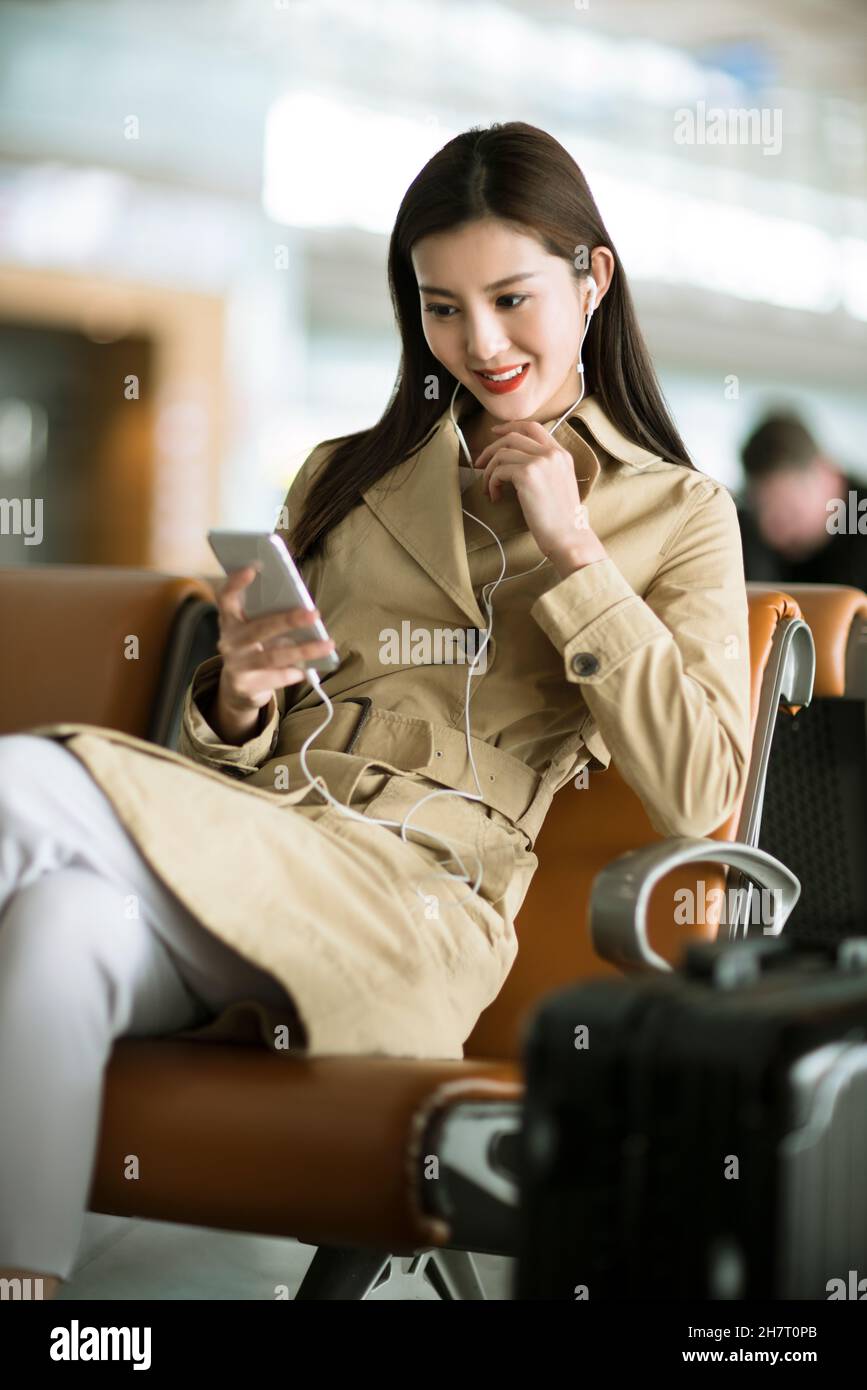 Femme d'affaires utilisant un téléphone portable à l'aéroport Banque D'Images