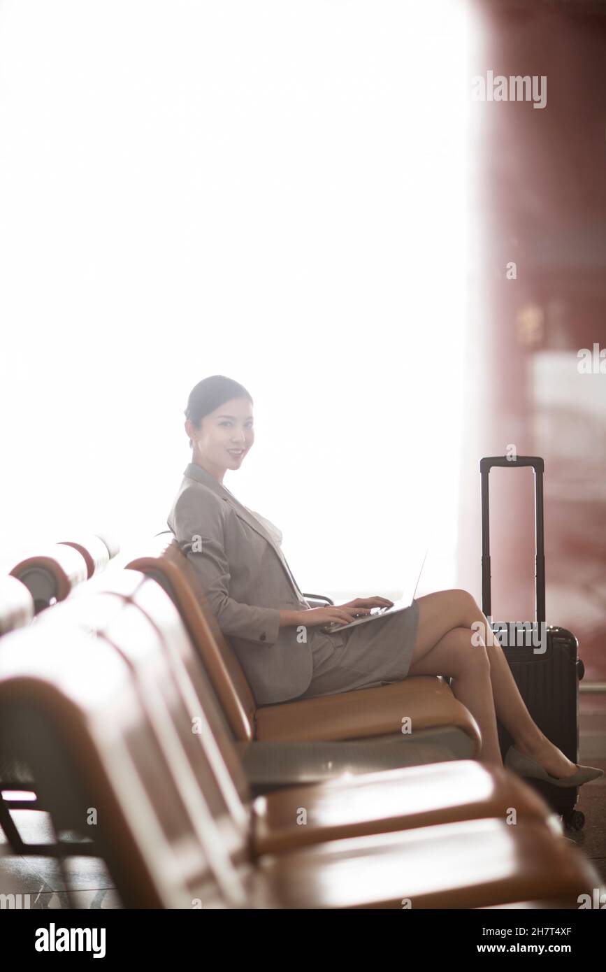 Jeune femme d'affaires utilisant un ordinateur portable dans la salle d'attente de l'aéroport Banque D'Images